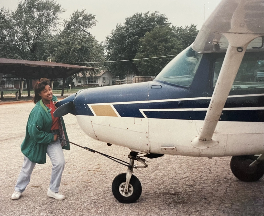 Origin story - Nia Gilliam at a young age standing in front of a small plane